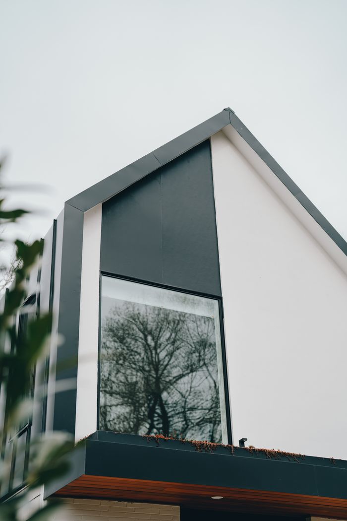 Contemporary house design featuring a large reflective window with a sleek facade.
