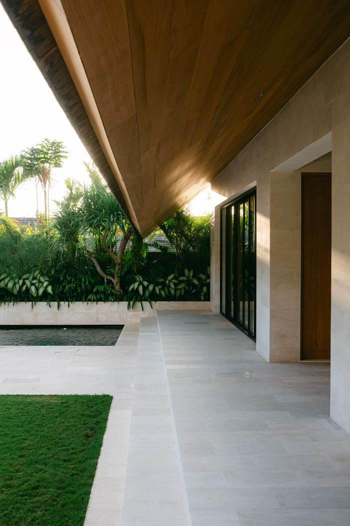 Elegant outdoor patio design of a tropical villa with greenery and sleek architecture.